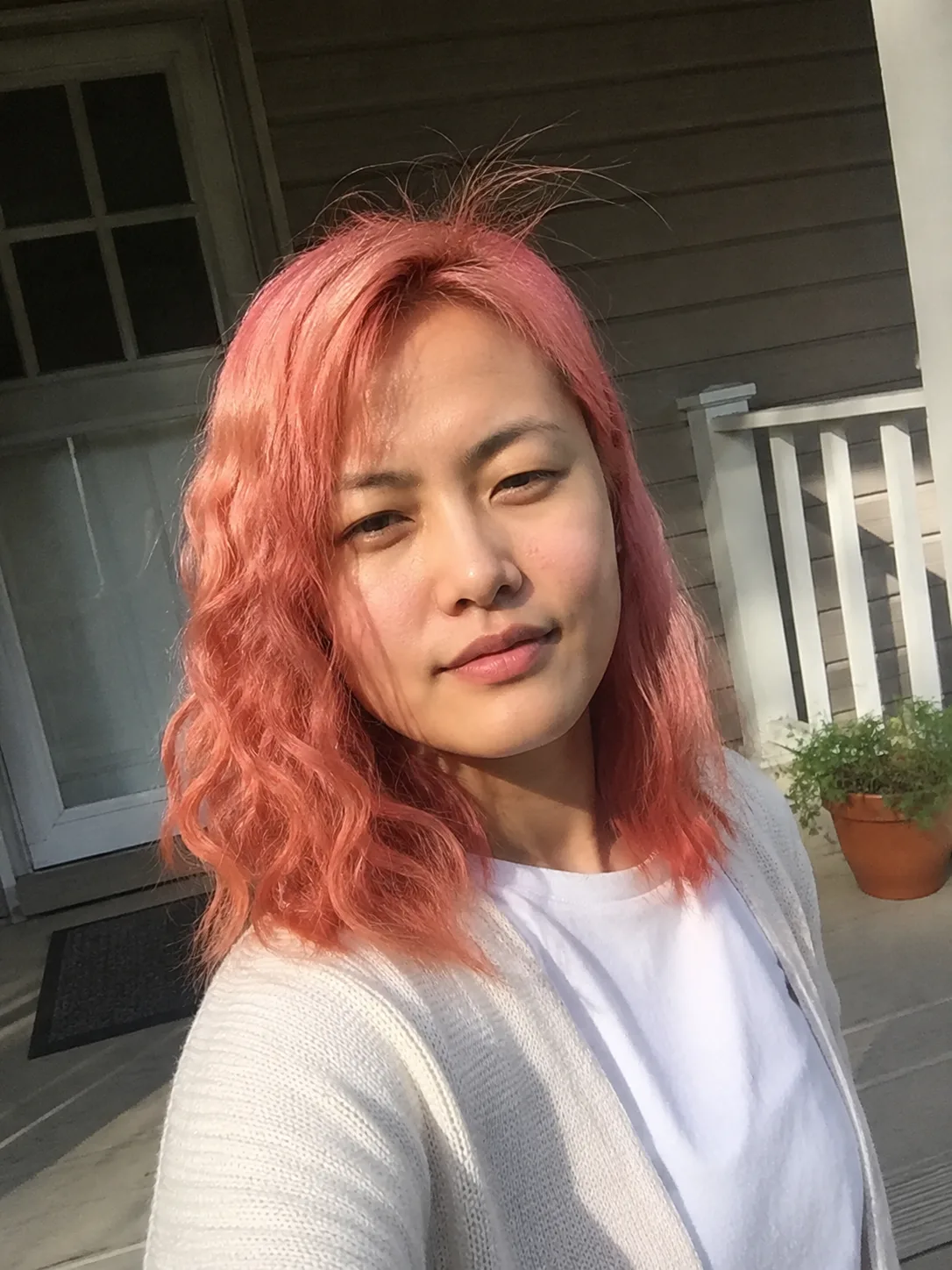 Watermelon pink hair color with bright red-pink tone and wavy shoulder-length cut.