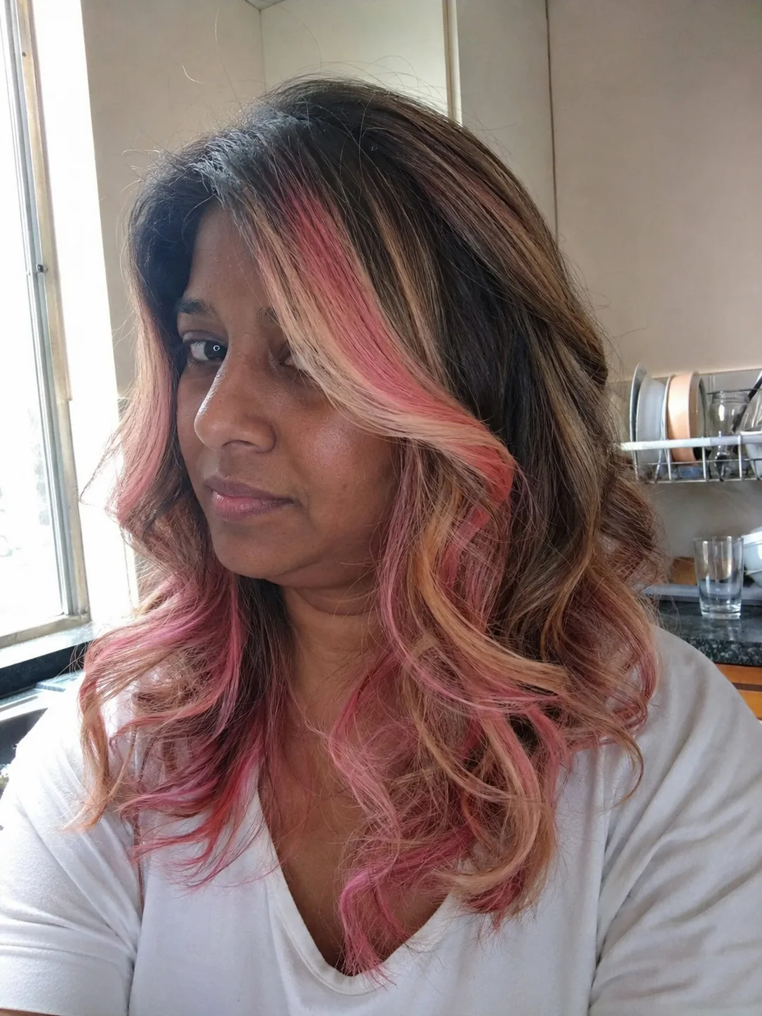 Rose-gold pink highlights on long dark brown hair