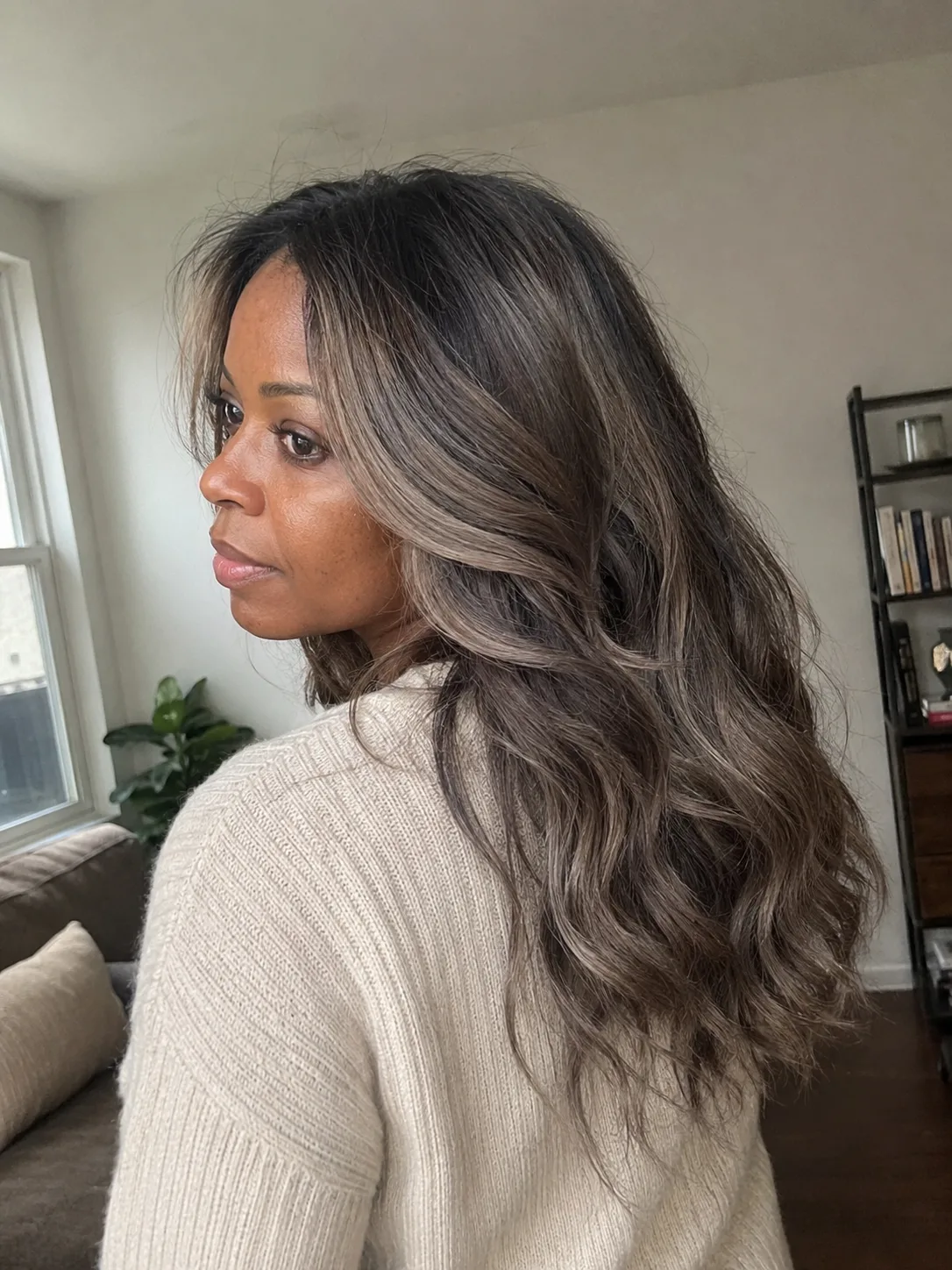 A bright portrait showcasing a textured, shoulder-length lob styled in loose waves with a brown base and prominent honey-blonde highlights