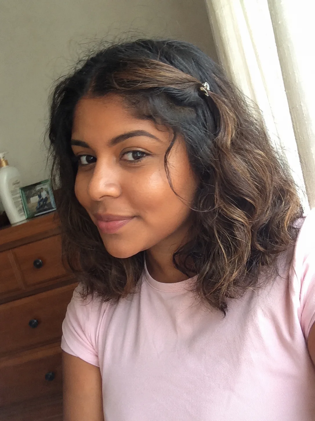 A casual, collarbone-length wavy style with a small front section pinned back neatly at the side with a clip
