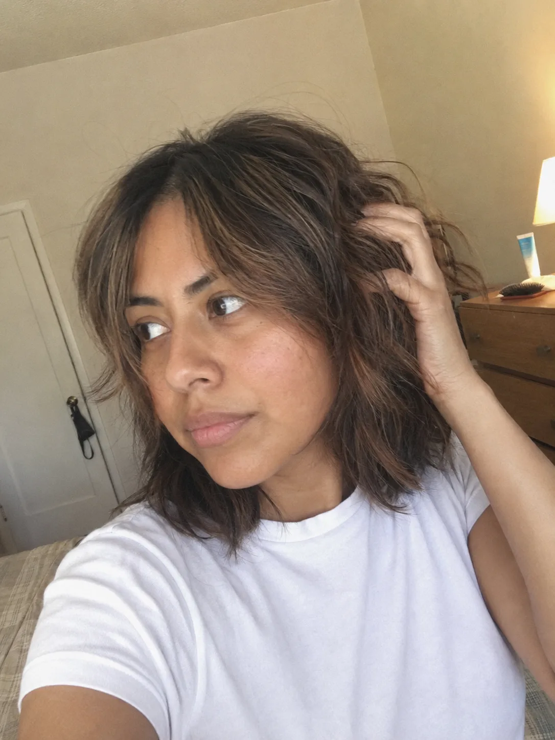A close-up view of a woman with a medium length haircut featuring highly defined, textured disconnected layers that create movement around the mid-lengths