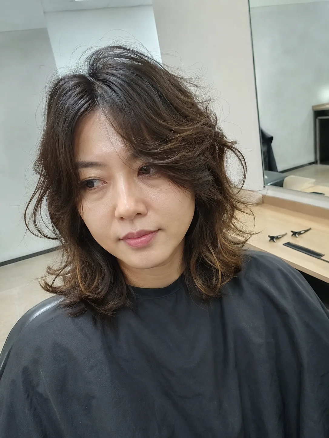 A heavily layered, shaggy medium-length haircut with face-framing curtain layers and soft, texturized waves