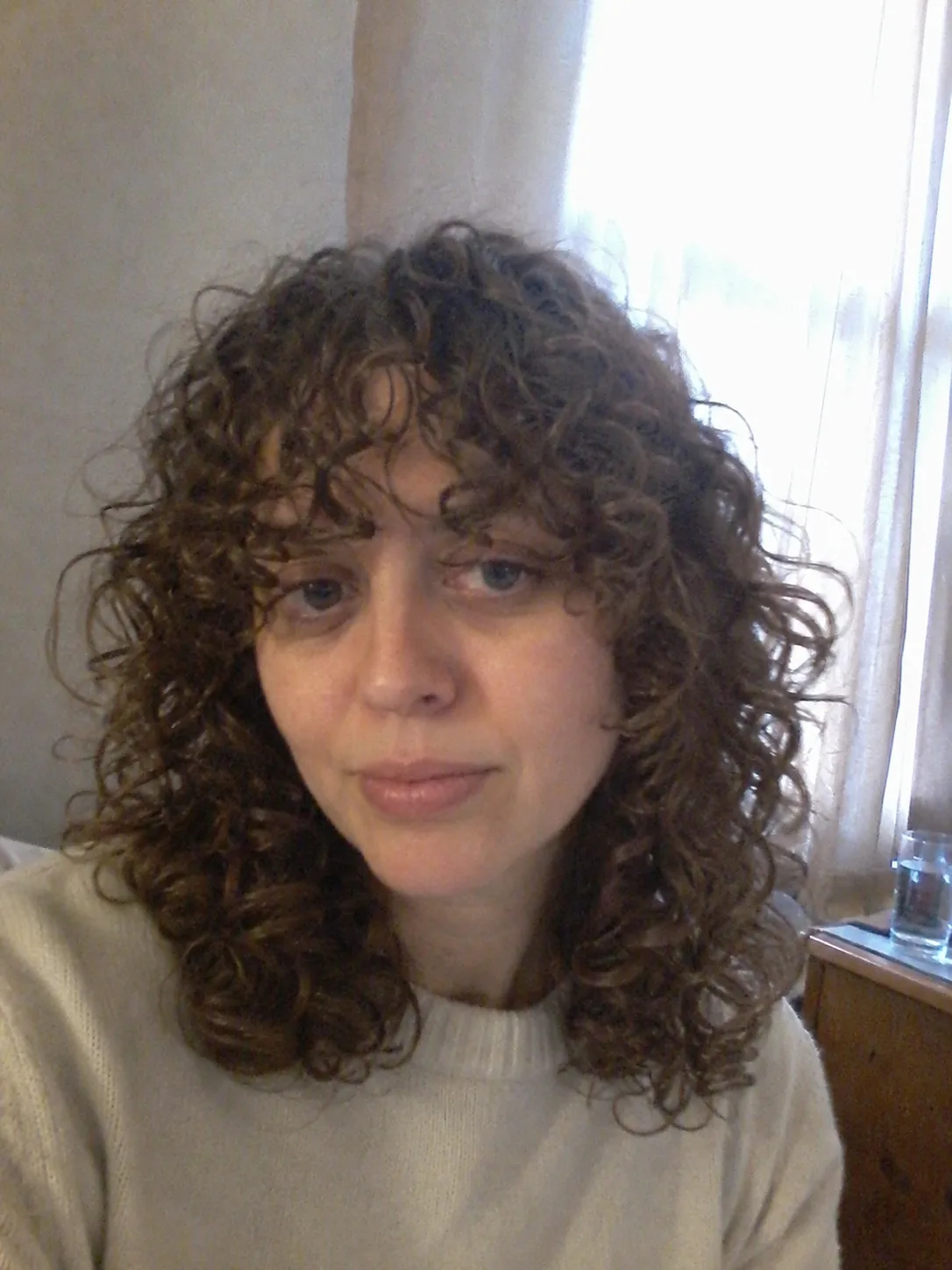 A high-volume curly ponytail with defined, elongated curls framing the face