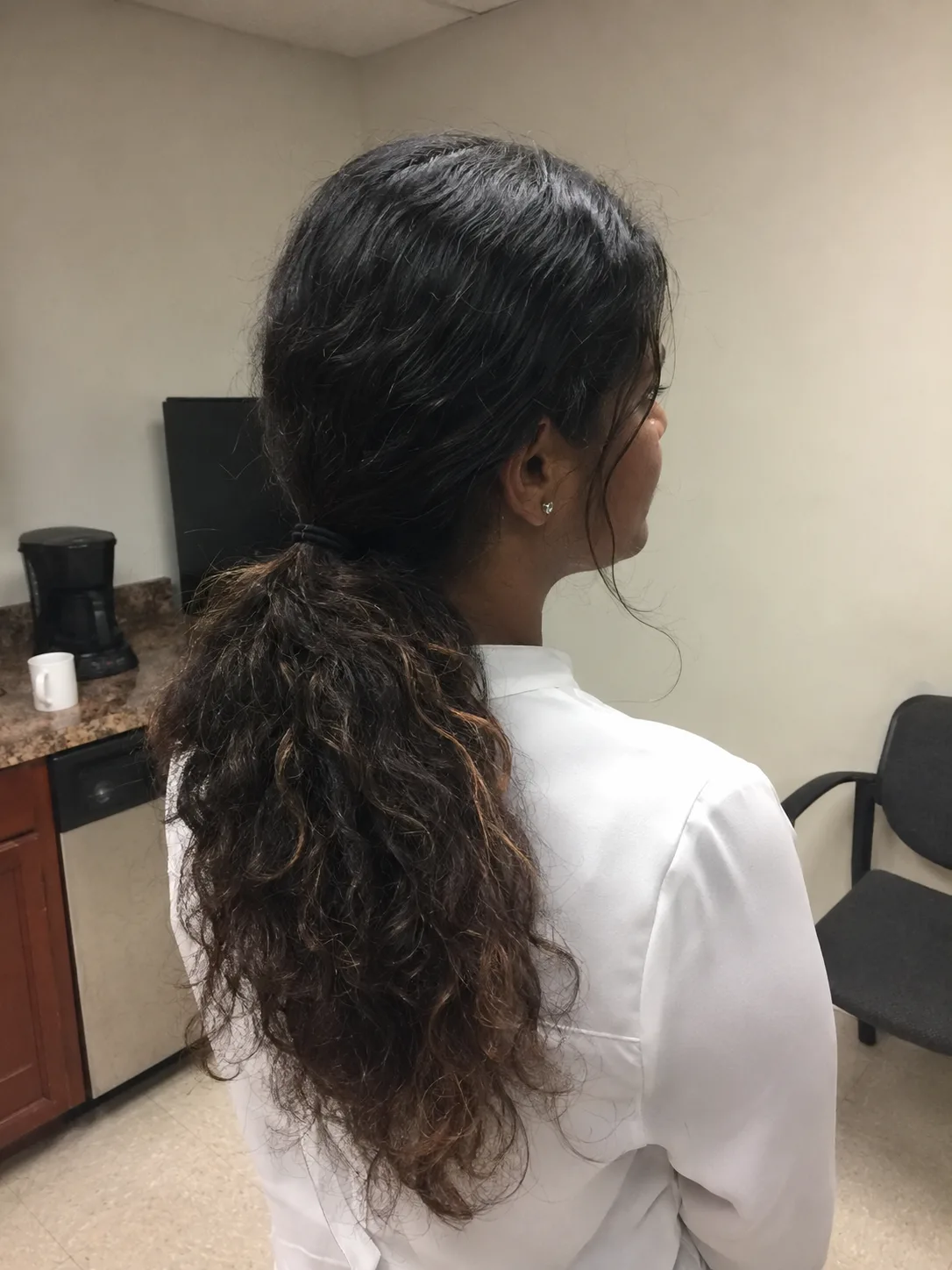 A low, relaxed ponytail at the nape of the neck gathering thick, multi-tonal waves for an effortless anchored look