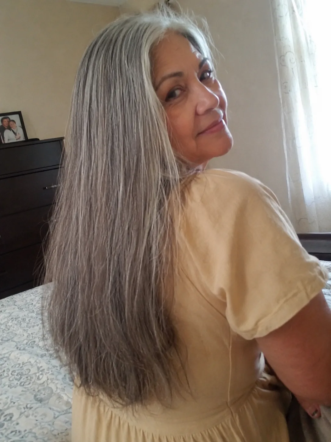 A mirror selfie of a woman over 60 displaying highly layered silver hair with shorter interior layers around the midlengths that separate slightly