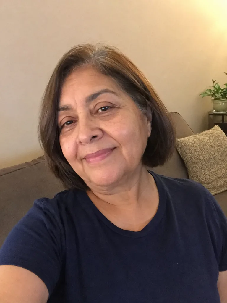 A mirror selfie of a woman showcasing a classic, textured grey pixie cut with long, side-swept layers across the front.