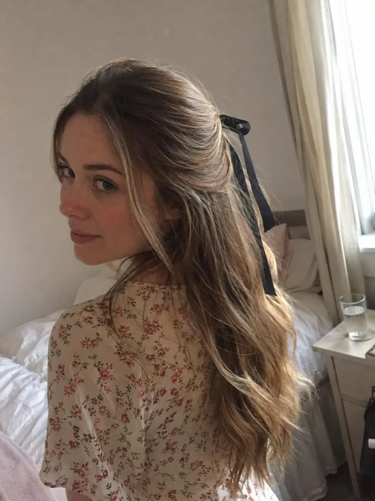 A mirror selfie of a woman with long hair styled in a half up look using a claw clip.