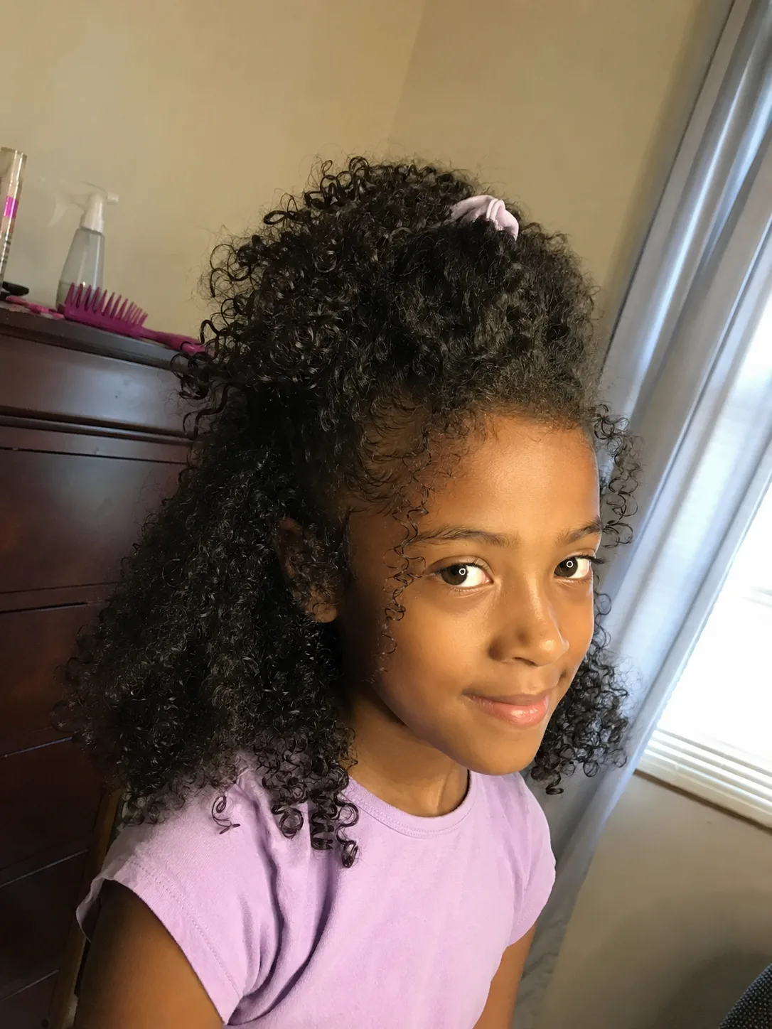 A mirror selfie portrait of a young girl with sleek, straight, shoulder-length black hair kept neatly pinned back on one side with two pastel hair clips