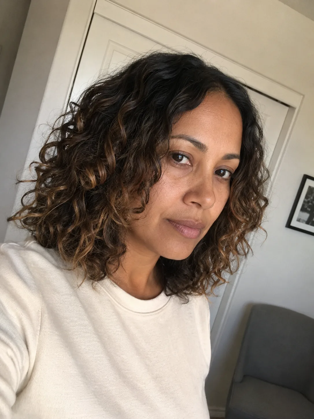 A person with medium-length, healthy, well-defined curly hair, showcasing natural volume and consistent texture.