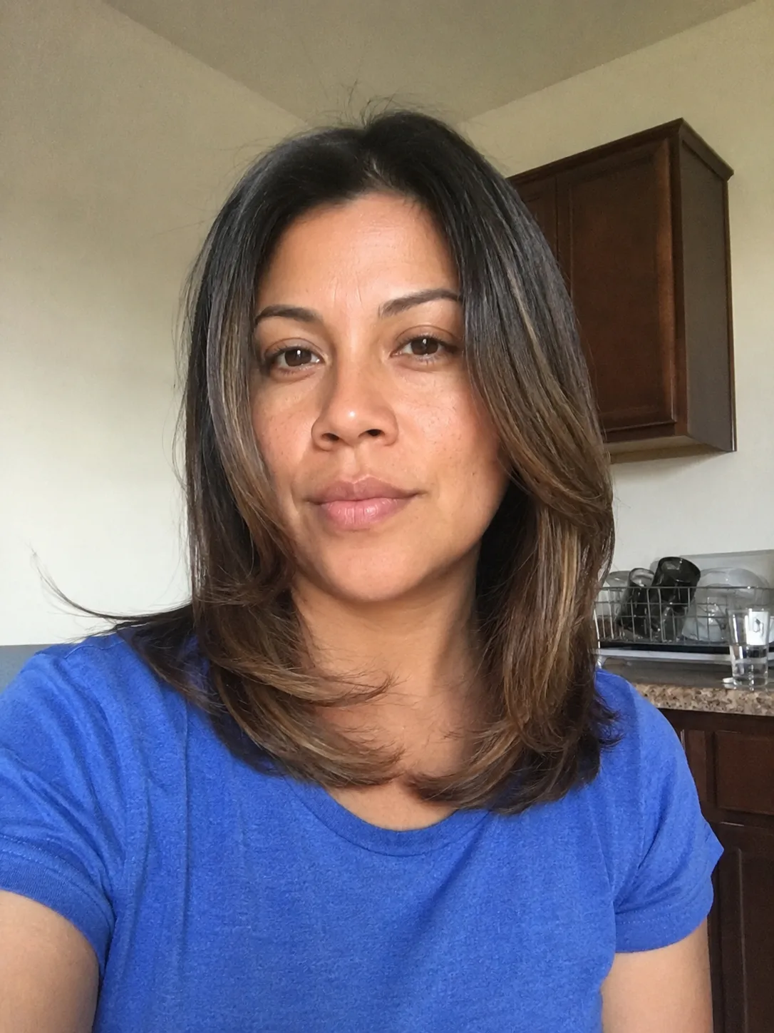 A portrait profile of a woman showing a soft, well-blended face-framing layer on a straight medium haircut that flows smoothly into the sides