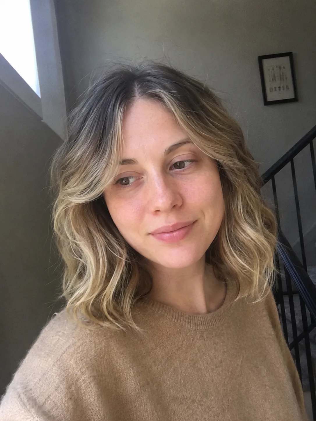 A portrait showing a direct view of a woman with a bouncy, rounded-shape curly layered haircut reaching the shoulders