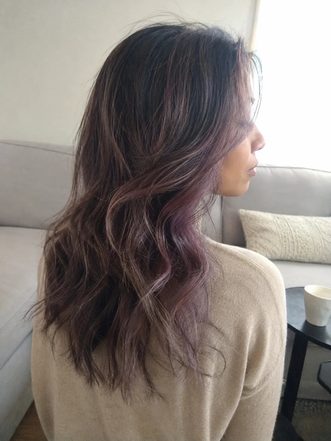 A selfie inside a vehicle showing a woman with a textured, shoulder-length wavy bob dyed a soft pastel peach and strawberry blonde blend