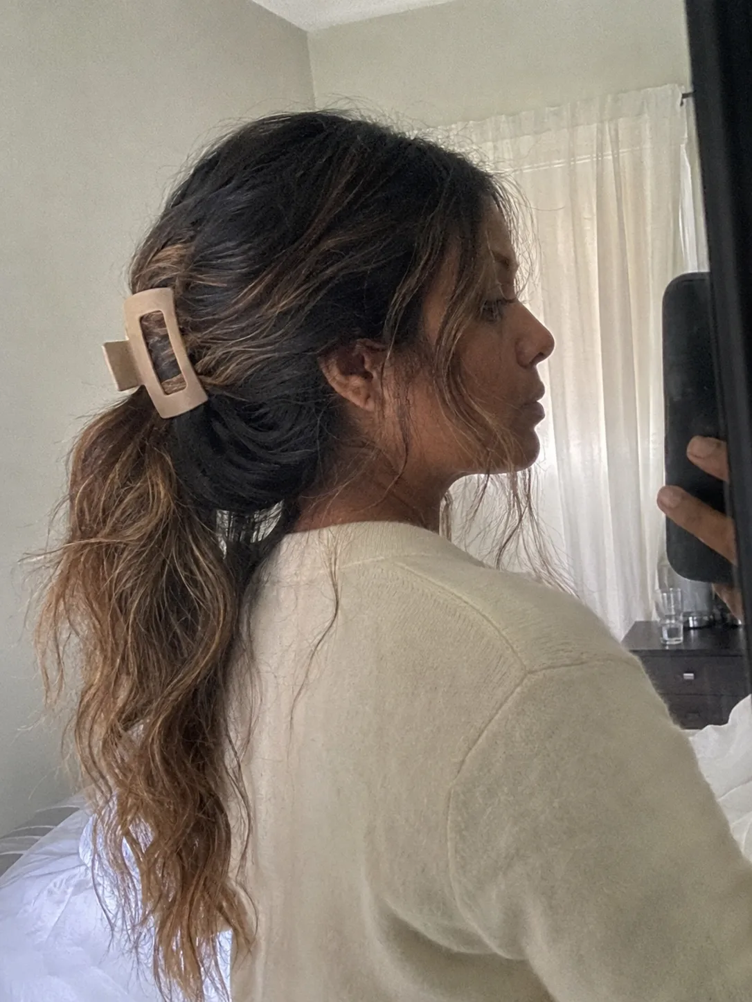 A selfie of a woman with a voluminous, loose, wavy ponytail.