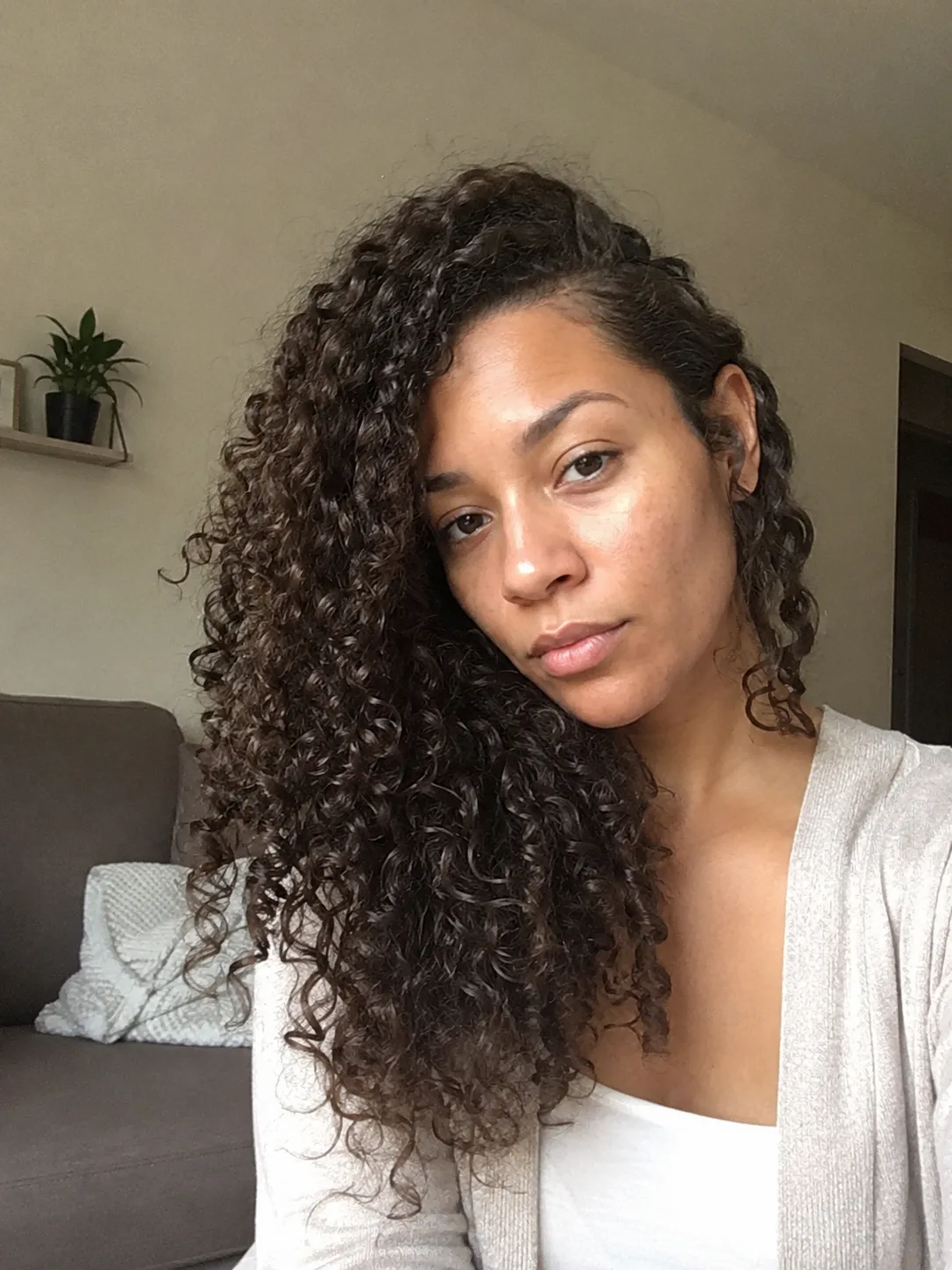 A shoulder-length, dark curly bob with defined ringlets and side-swept bangs