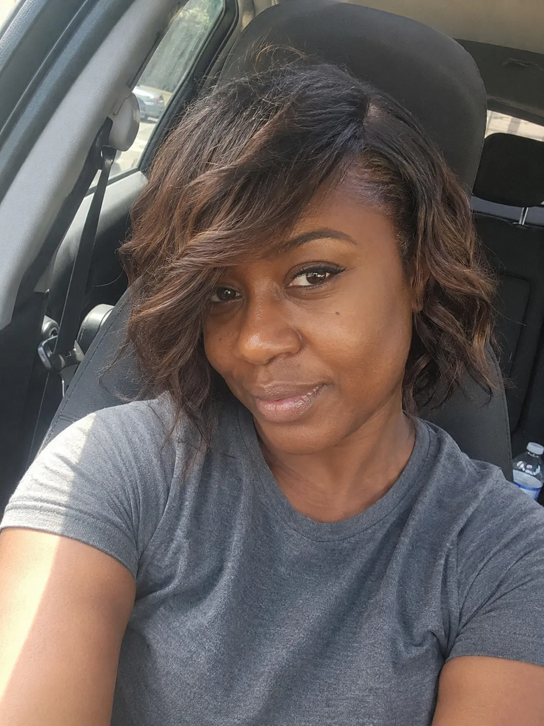 A side profile selfie of a woman showing a modern, closely tapered dark pixie cut with smooth, neat side-swept front layers
