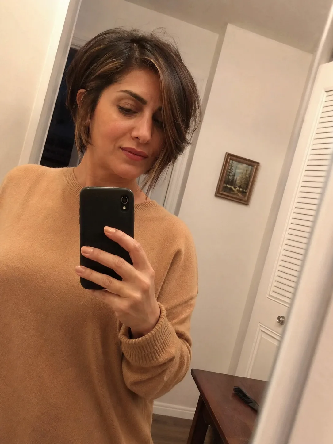 A side profile view of a woman with an asymmetrical, sleek dark inverted bob haircut featuring a long, clean side-swept fringe
