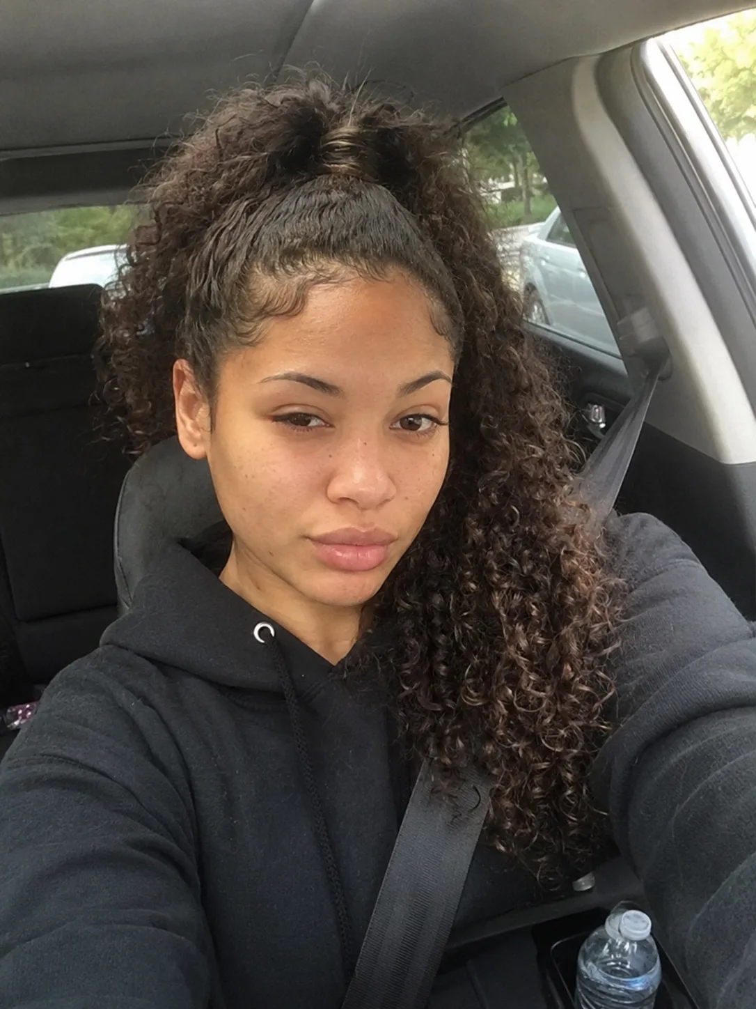 A sleek high curly bun showing expert root control and volume at the crown