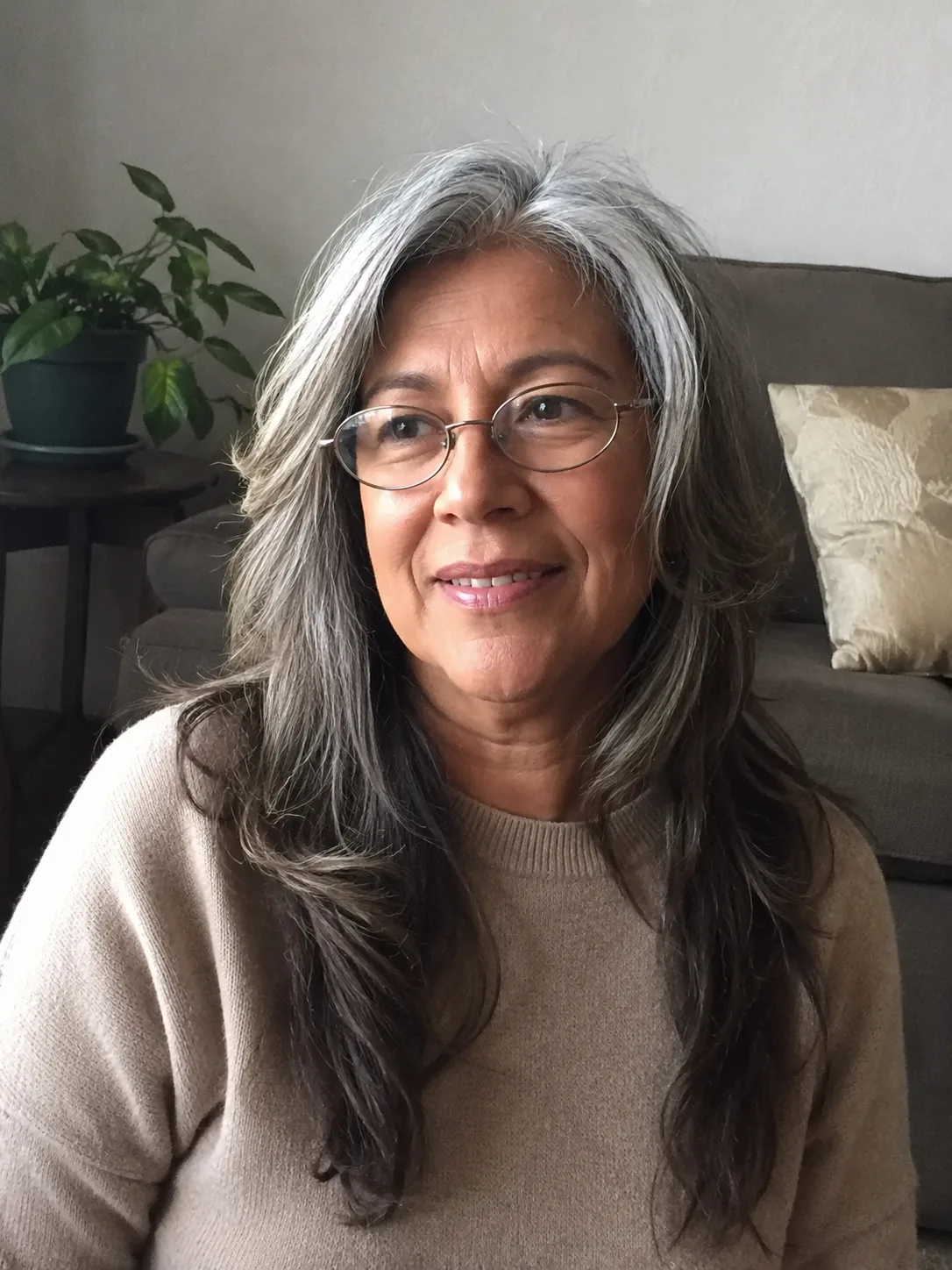 A smiling woman wearing glasses, showcasing a short, tightly coiled grey afro haircut with natural texture