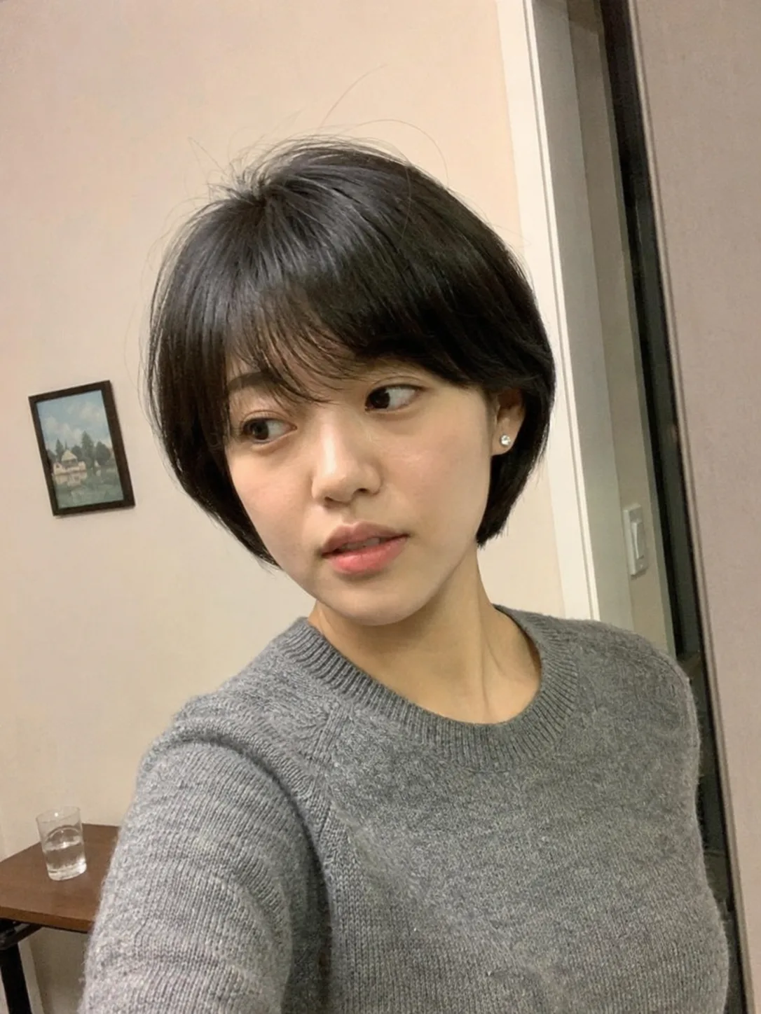 A smiling woman with a dimensional chin-length bob haircut featuring multi-tonal highlights and soft, texturized layers flipping slightly outward
