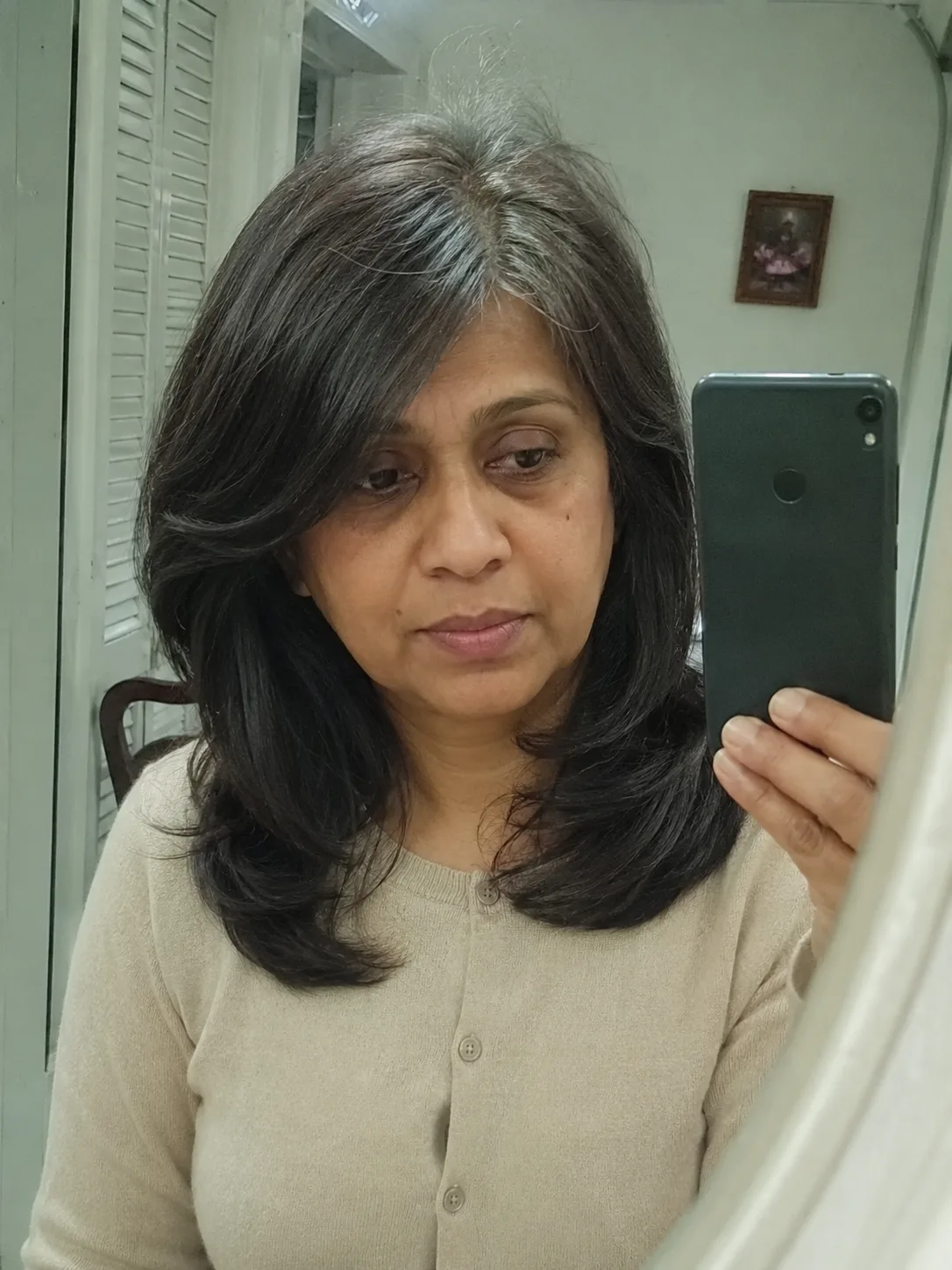 A woman looking forward, displaying smooth, healthy ends on a layered medium haircut that avoids over-thinning in the mid-shaft