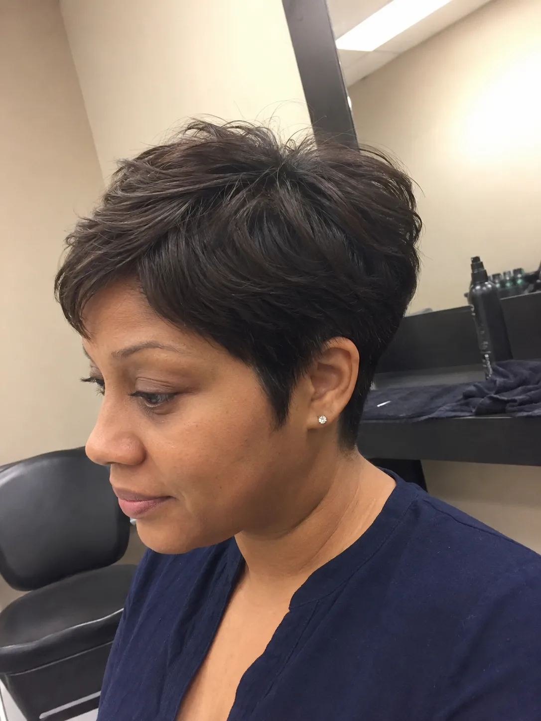 A woman looking to the side showcasing a smooth, rounded classic dark bob haircut with soft uniform layers framing the face