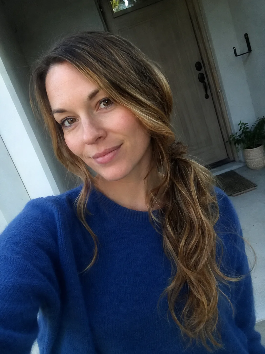A woman with a loose, wavy side ponytail and soft face-framing layers
