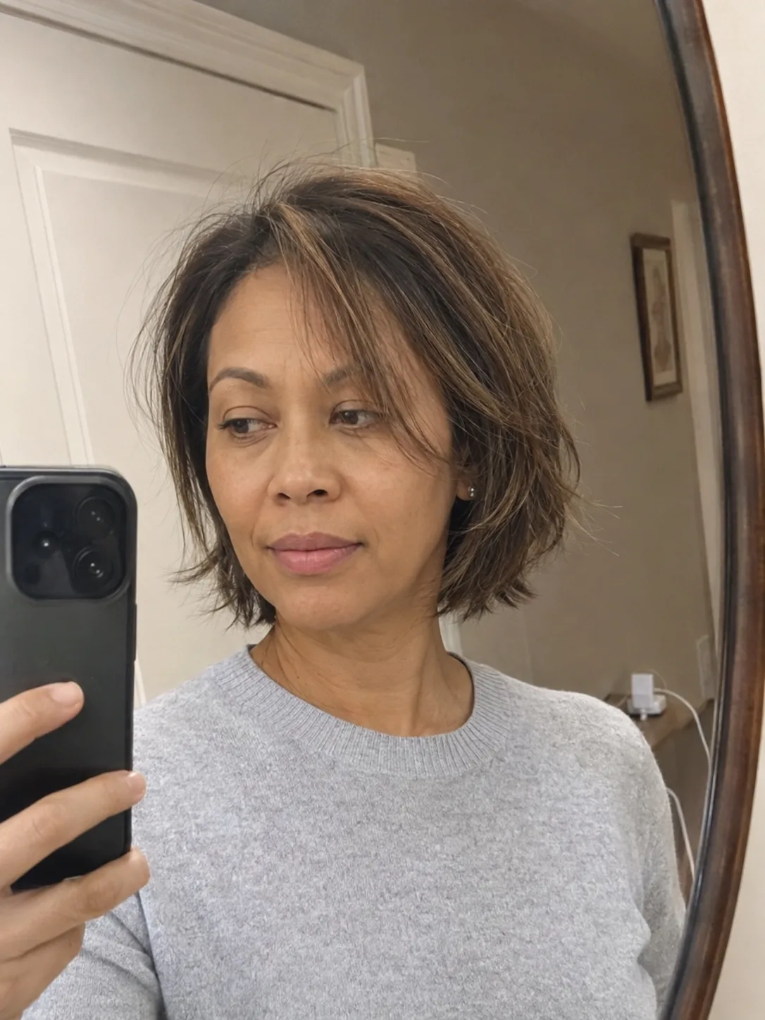 A woman with a medium-length texturized bob haircut with a side parting, showcasing dimensional brunette tones and soft, relaxed layers