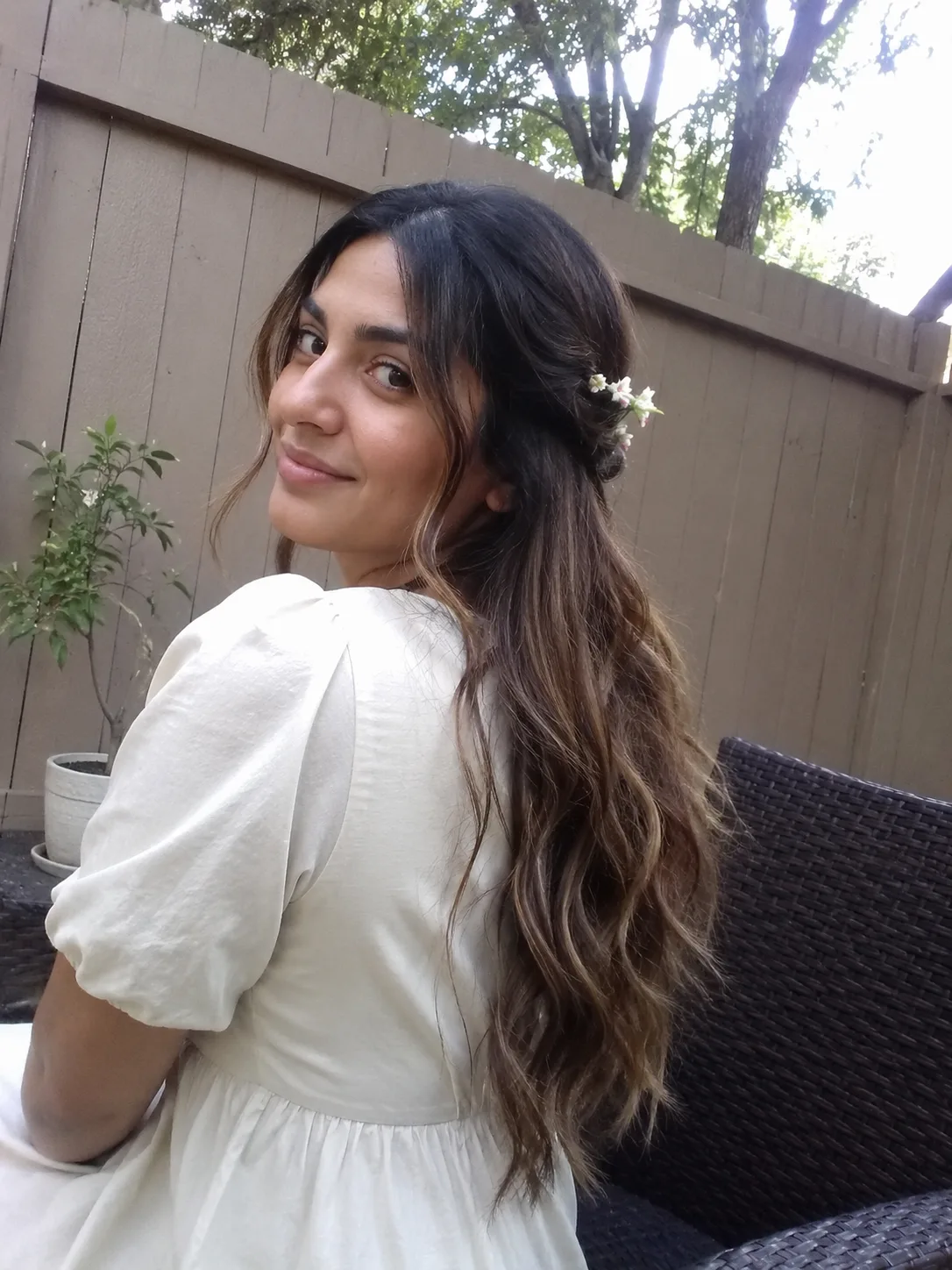 A woman with curly hair styled in a half up fashion with face-framing curls