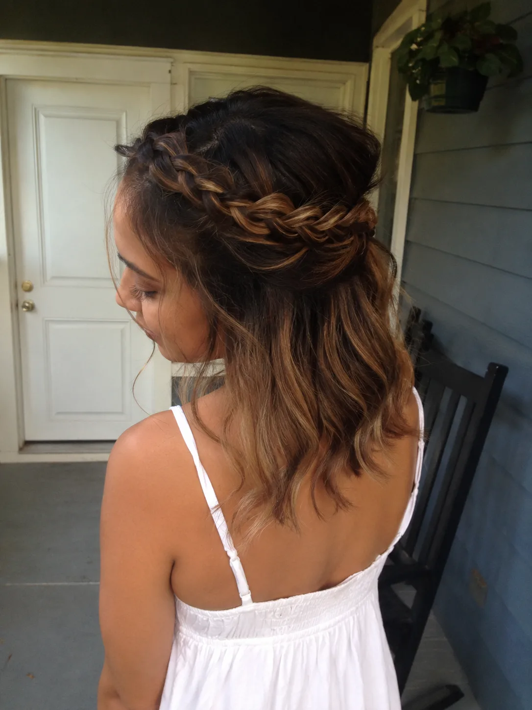 A woman with medium-length wavy hair featuring two thin braids on either side of her face