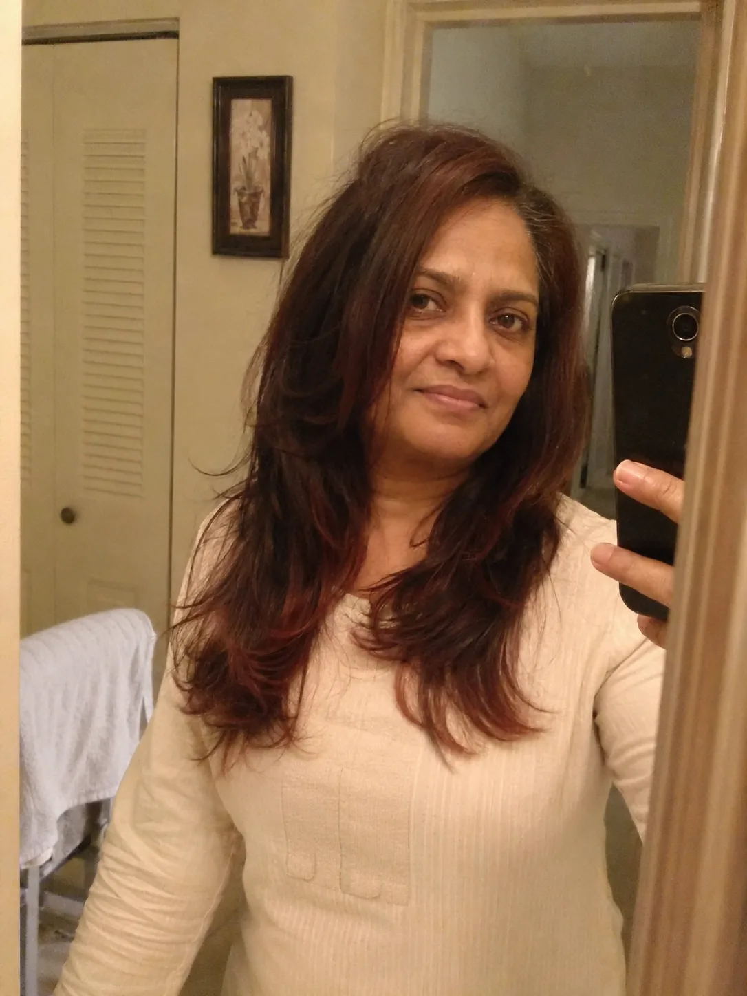 An all-over bright, warm ginger and copper shade on textured, shoulder-length wavy hair catching natural soft light
