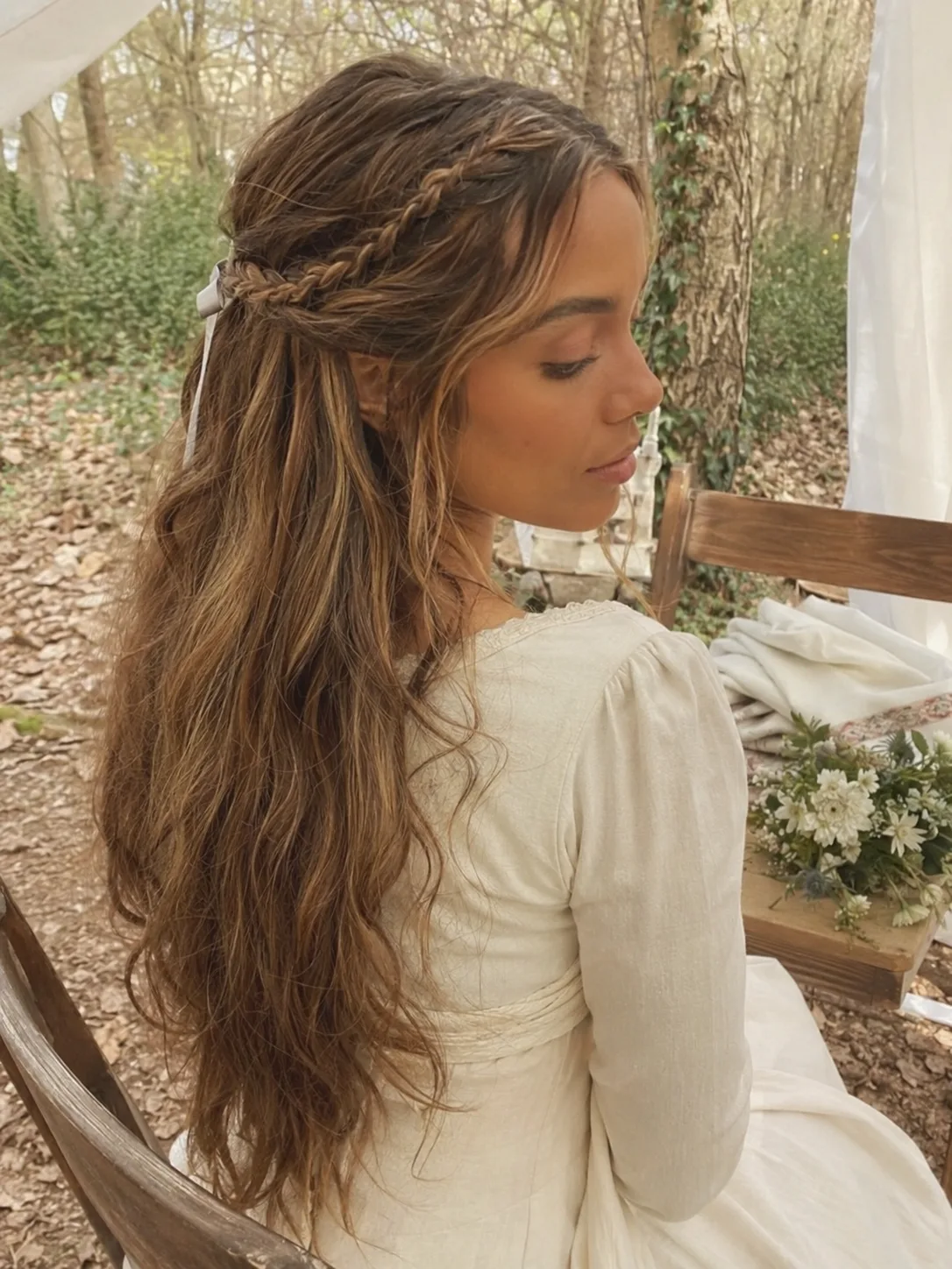 Back view of a woman wearing a brown linen dress with a single, long, thick three-strand flat braid tied at the end with an olive green fabric ribbon
