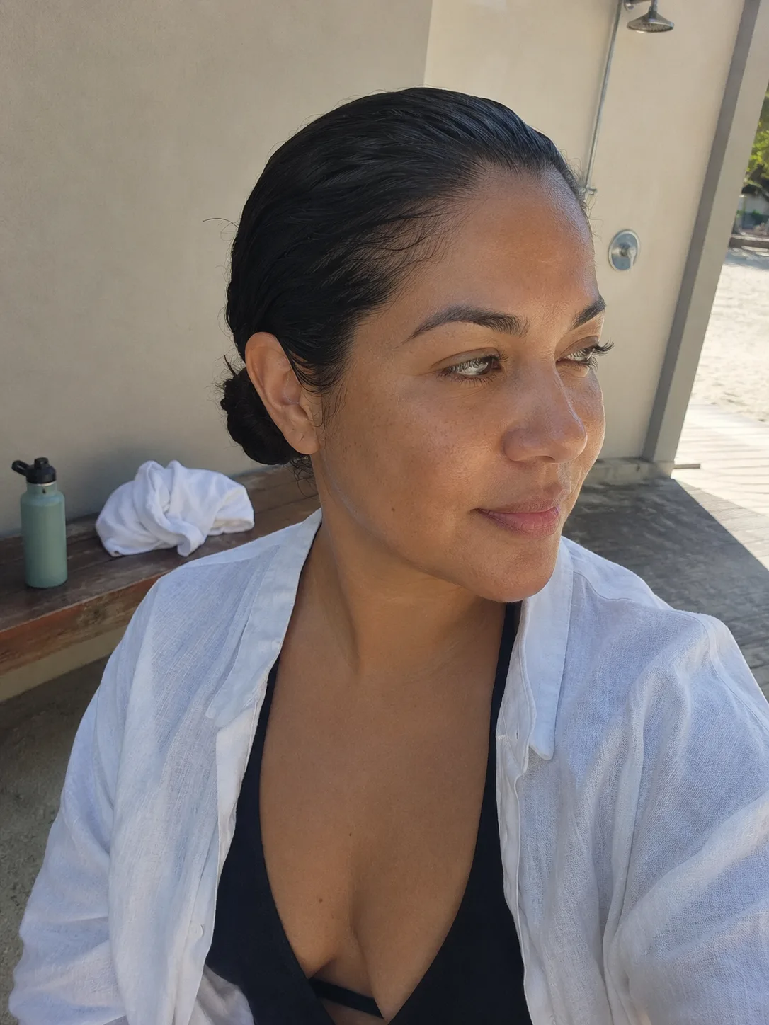 Damp wet look low bun after swimming with white beach cover up