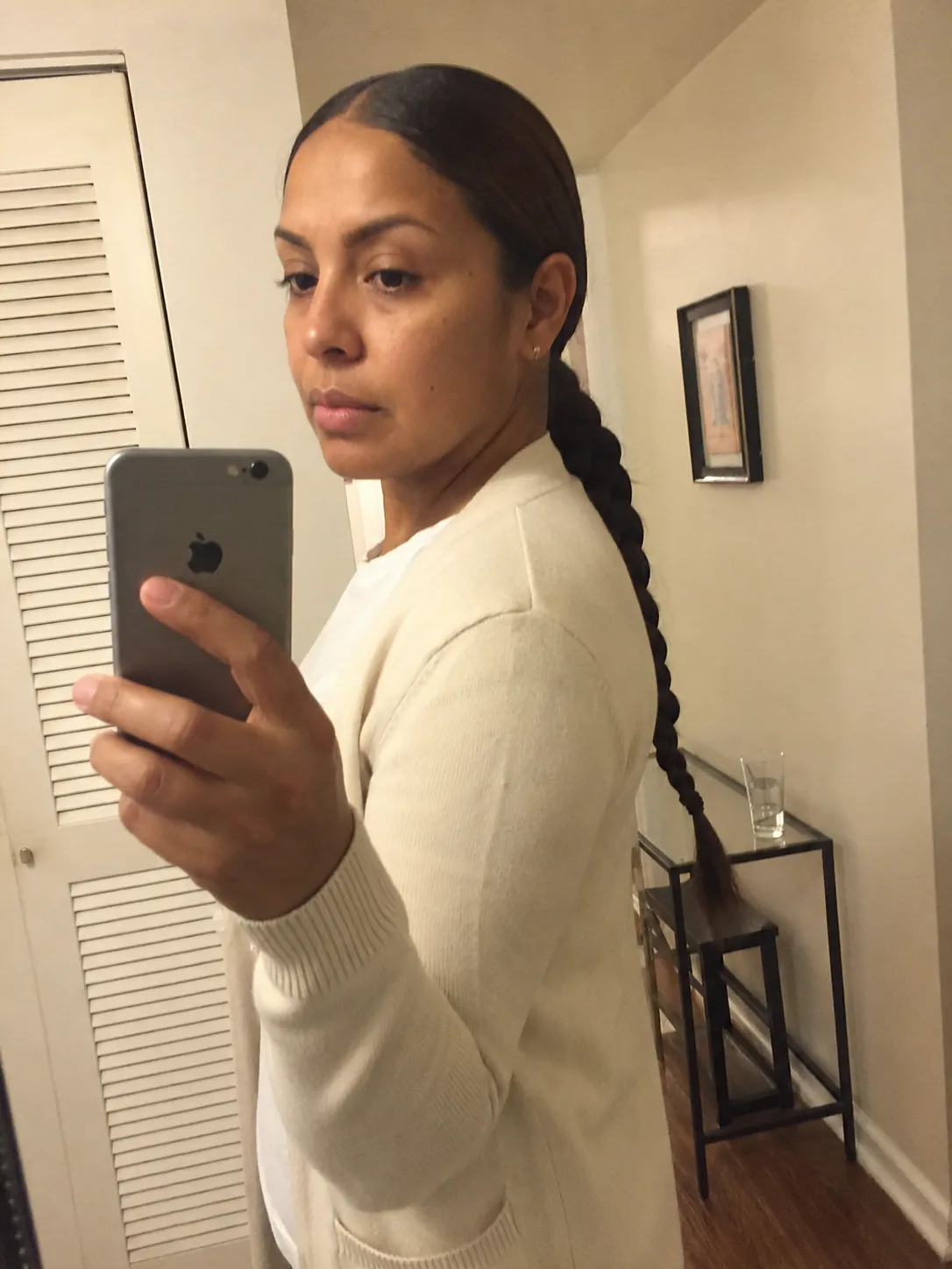 Hairstylist hands adjusting and securing the smooth base of a high ponytail from the back view