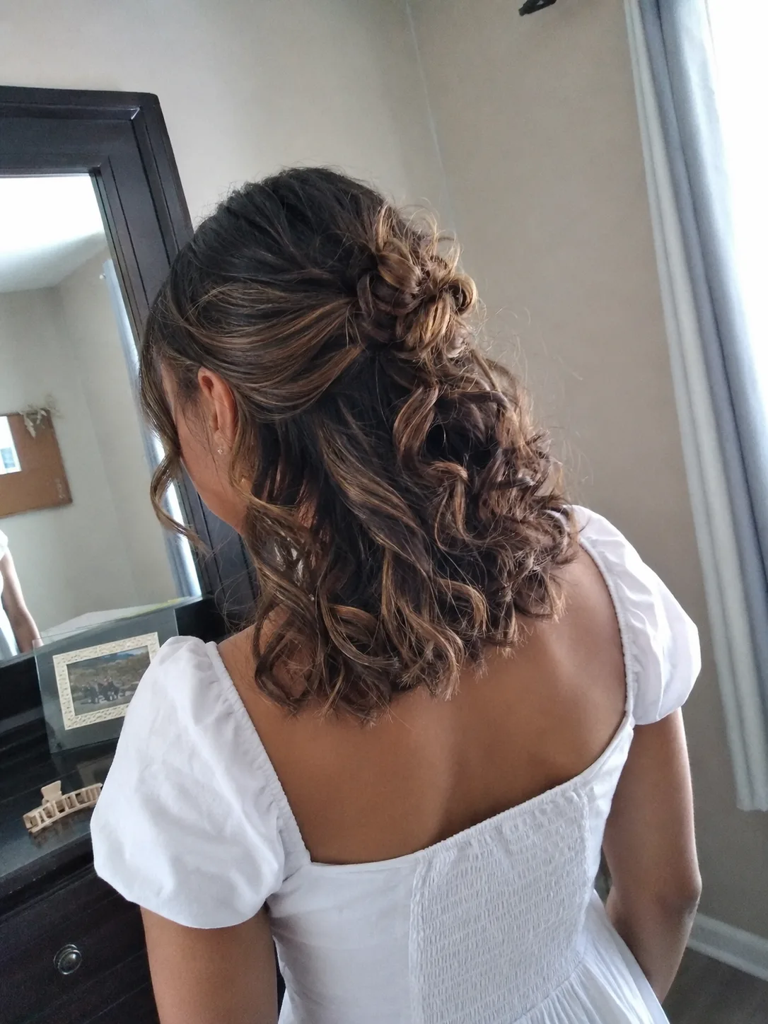 Half-up curled prom hairstyle for medium length hair with pinned back detail.