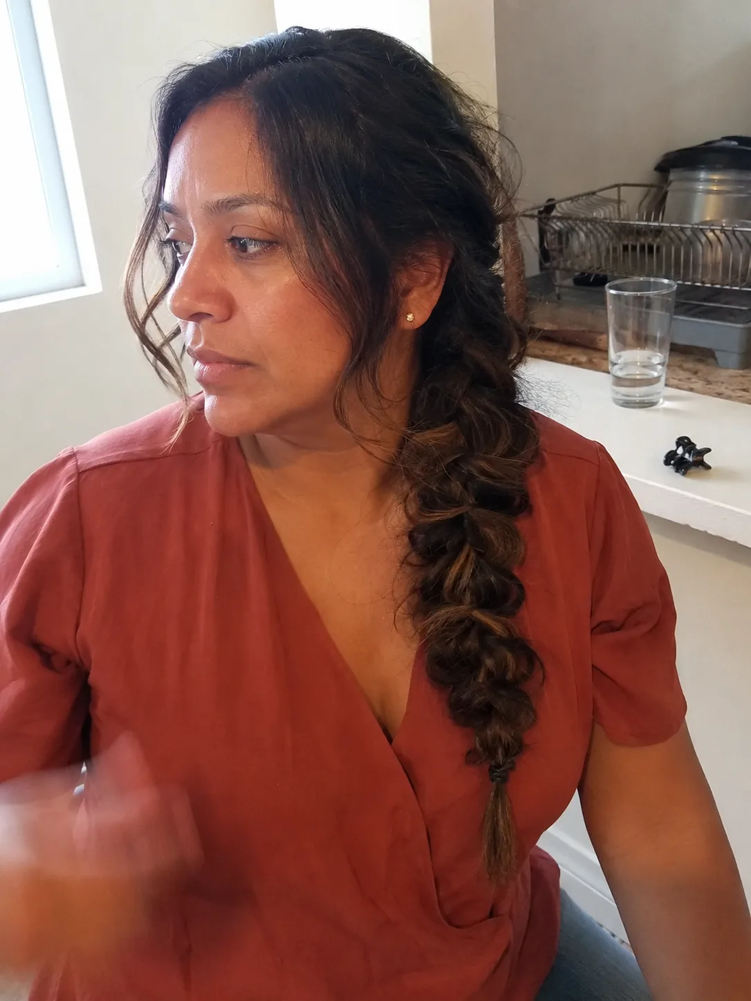 Long brunette hair braided into a structured loose style anchored firmly at the nape of the neck