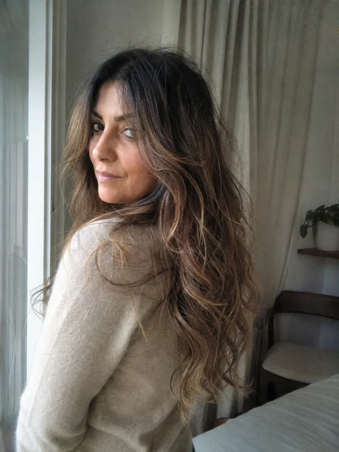 Long, flowing layered hair with sun-kissed highlights, showcasing effortless beachy texture and natural volume.