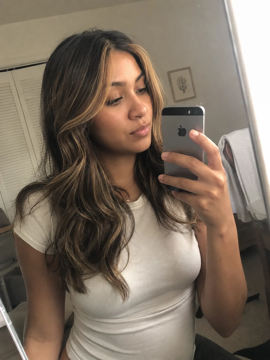 Long, layered wavy hair with a dark base and warm caramel and golden-brown highlights, captured in a salon setting