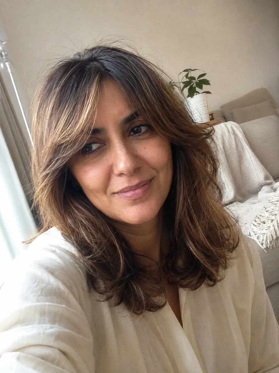 Straight medium-length hair with wispy bangs and layered ends
