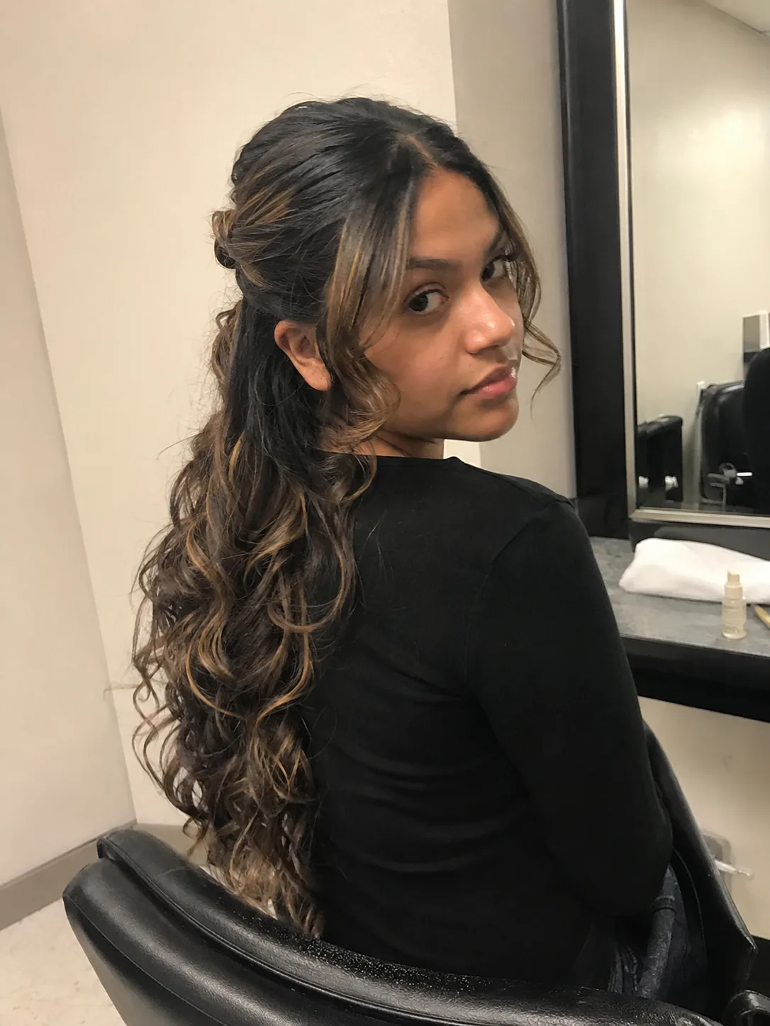 Mirror selfie showing a half-up top knot to illustrate elastic hold vs