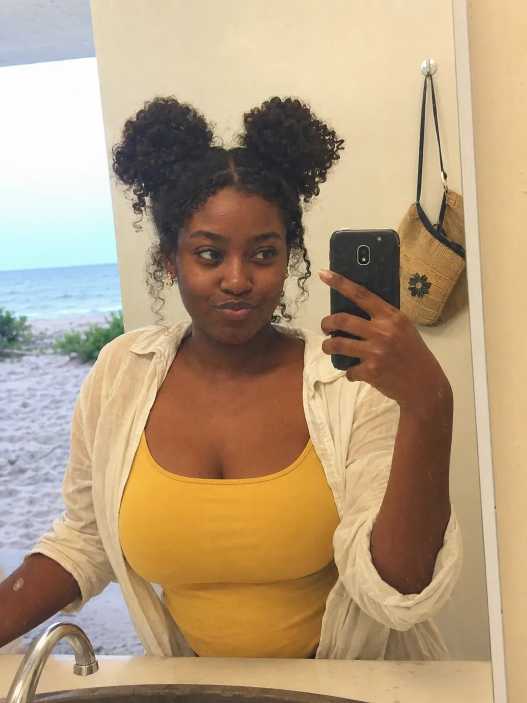 Natural textured space buns with loose curls in a beach restroom mirror selfie