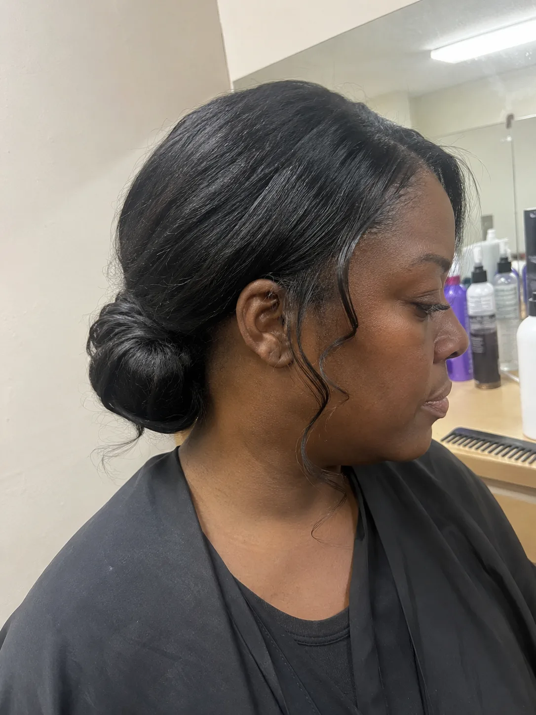 Polished back view of an elegant wedding guest updo featuring structured low loops on long dark hair