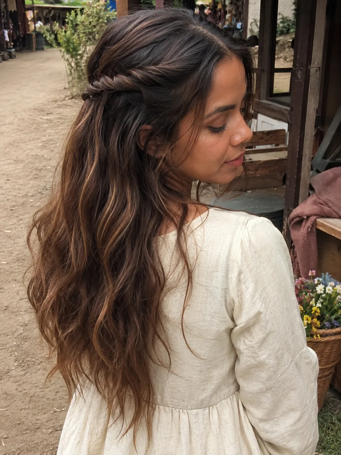 Rear side view of a woman with a low medieval bun updo featuring tight, twisted side sections pulled flat against the scalp