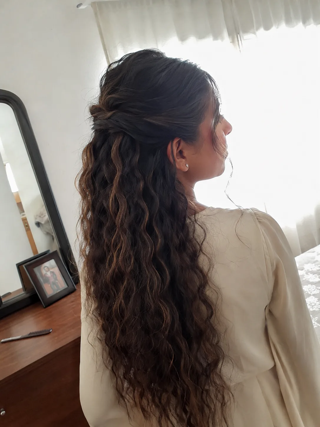 Short, tight face-framing curl waves paired with a high-retention formal half up
