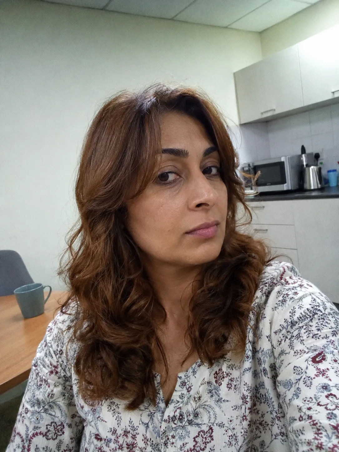 Side profile view of a woman showing deep plum and dark magenta highlights woven beautifully through long, voluminous dark curls