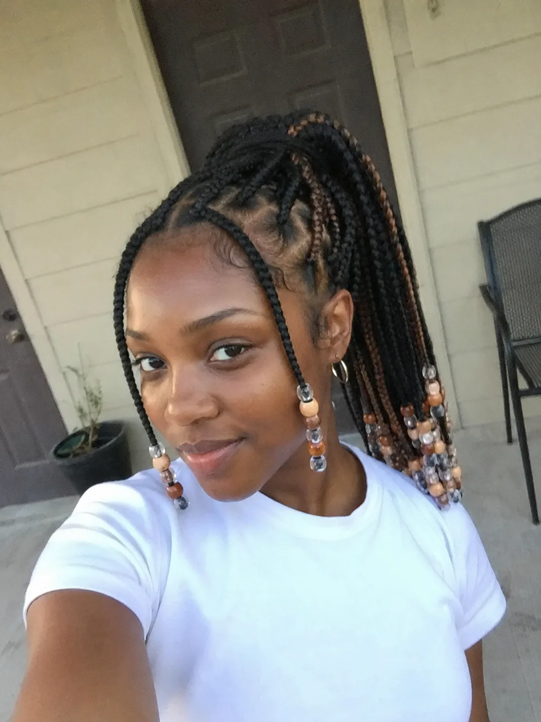Side view of a mid-height braided ponytail with neat curved cornrows and face-framing accent braids decorated with brown wooden beads
