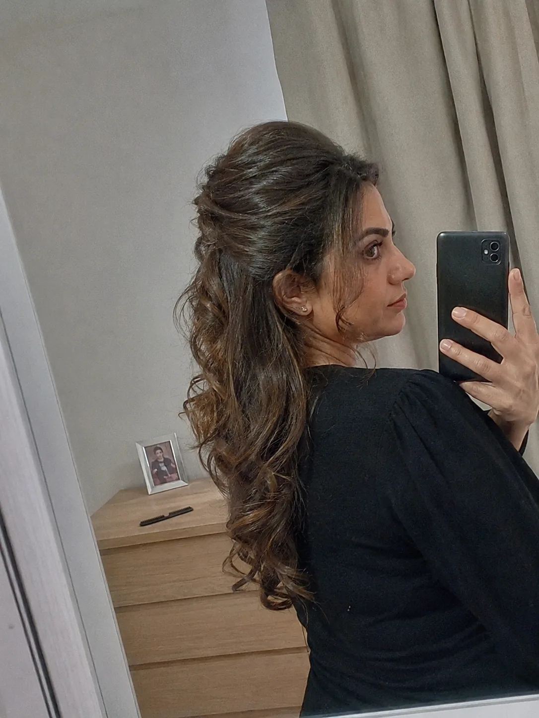 Smoothly gathered half-up style on long caramel-toned hair highlighting clean side section lines