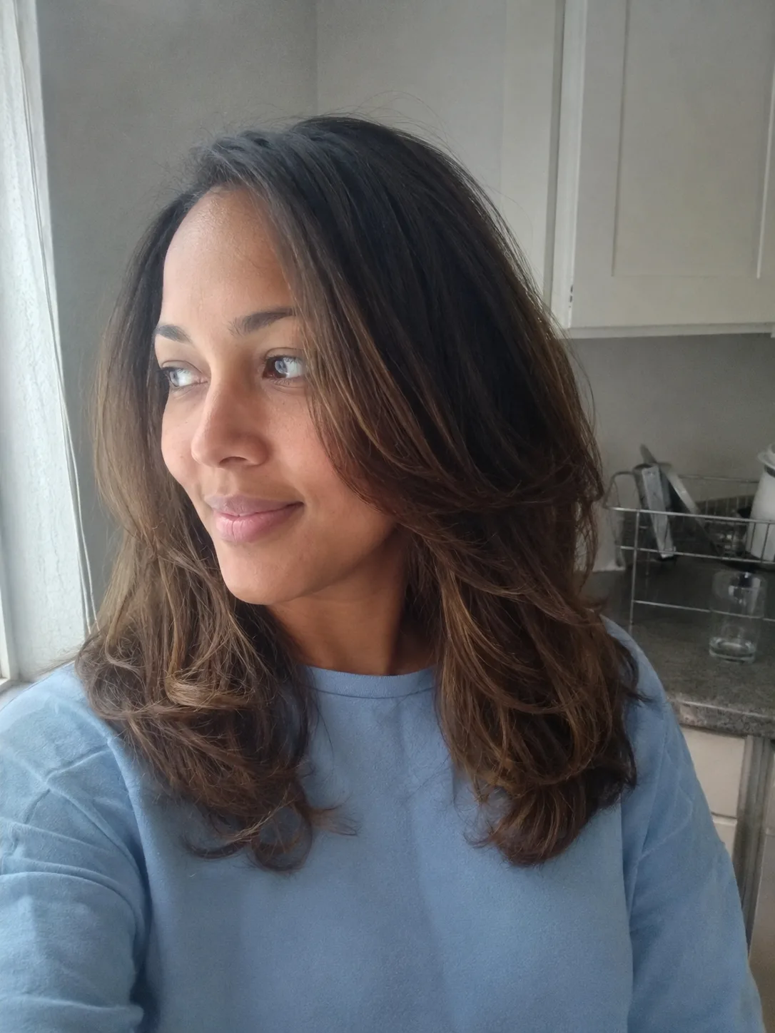 Soft layered blowout hairstyle with natural movement and face framing pieces