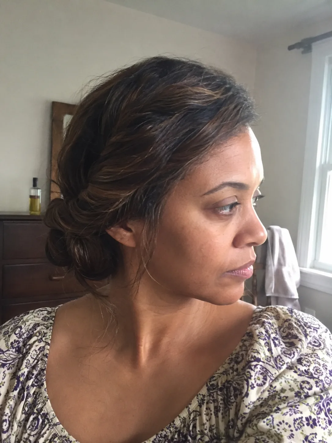 Soft twisted low bun on textured hair with loose face framing pieces