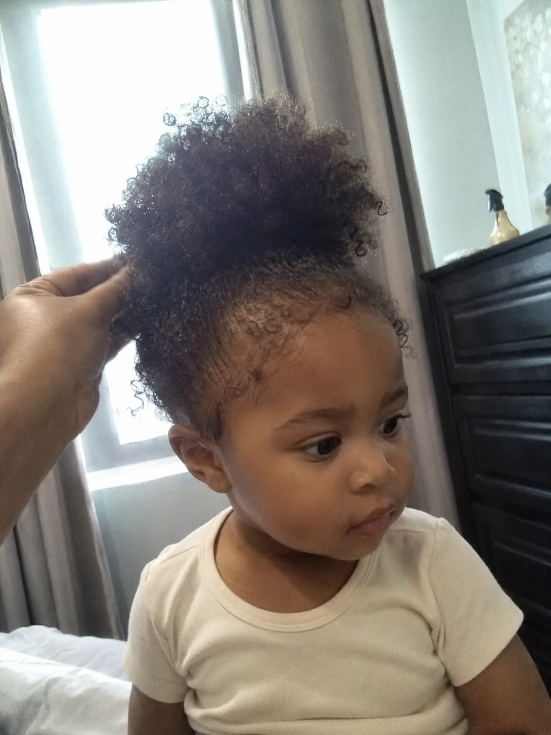Soft, weightless baby hair neatly secured on top to manage dual hair textures on a toddler