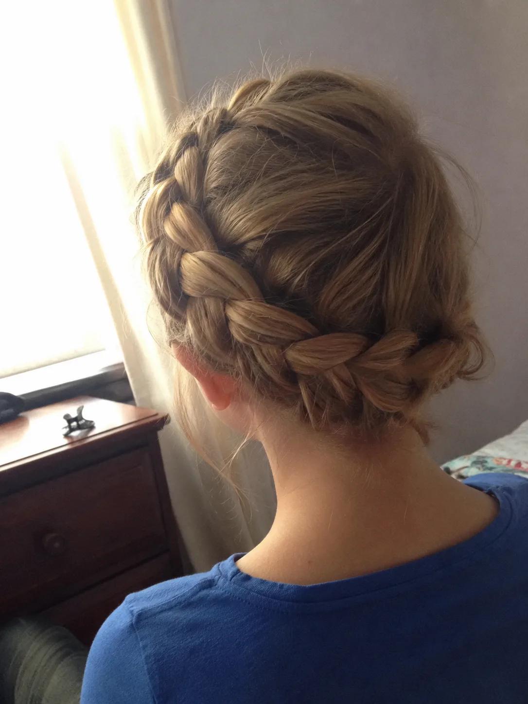 Stylist adjusting textured low prom updo on long hair